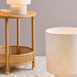 Let sidebord i rattan med vase og levende lys i varm boligindretning