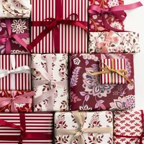 Julegaver indpakket i m�nstret papir med r�de, rosa og vinr�de b�nd fra Bungalow